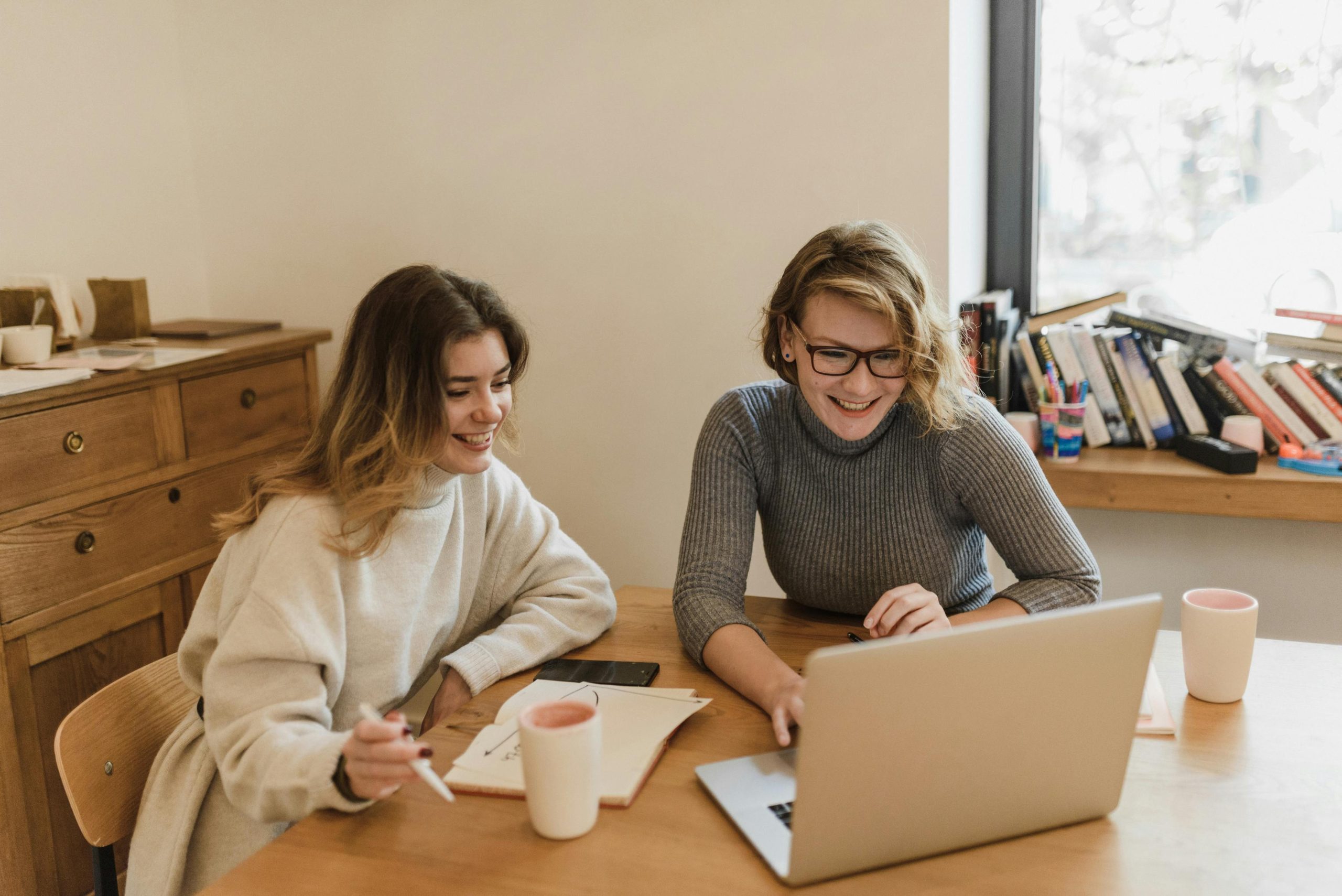 pexels-photo-6016359-6016359 Two women happily collaborating in a contemporary office setting.